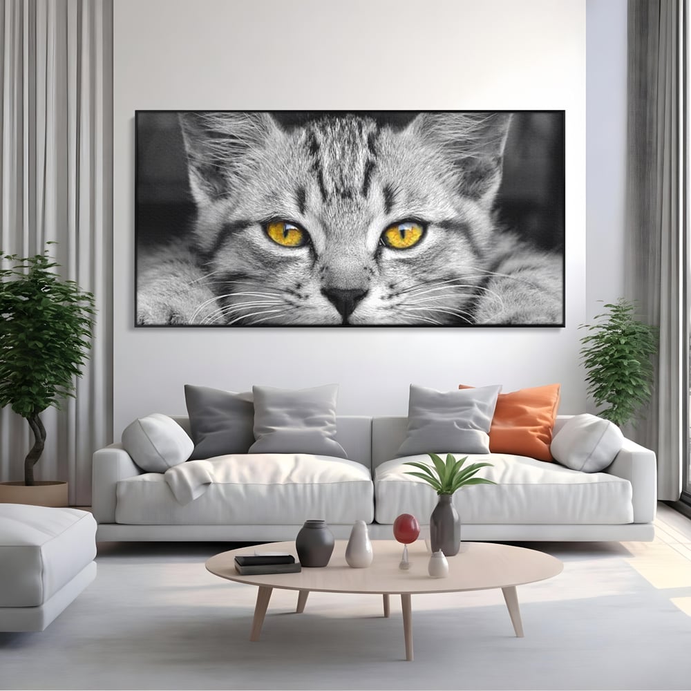Tablou canvas cu tablou canvas cu o pisica alb-negru si ochi galbeni, in rama de aluminiu negru, pe perete intr-un living